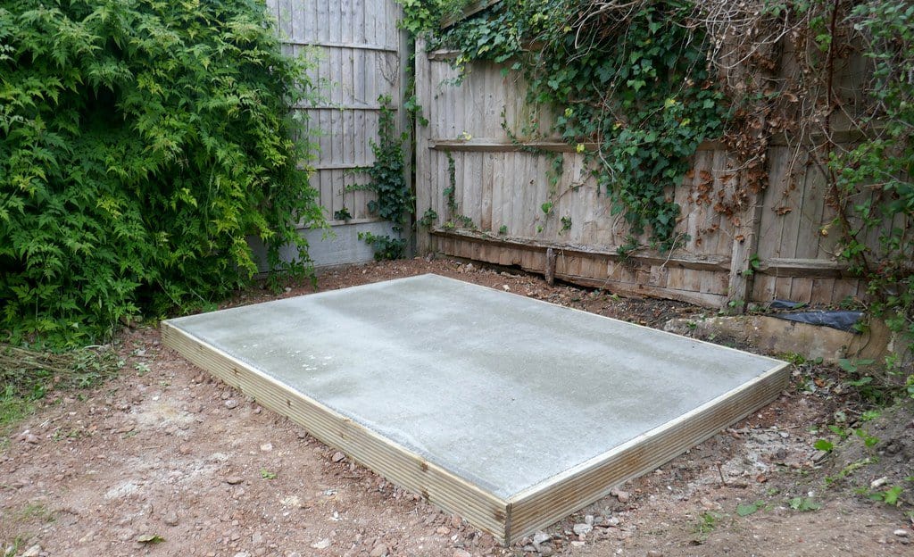 Corner placement of a shed base in a backyard.