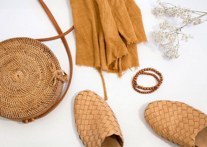 tan fabric, bag, bracelet, and shoes on a white surface with flowers