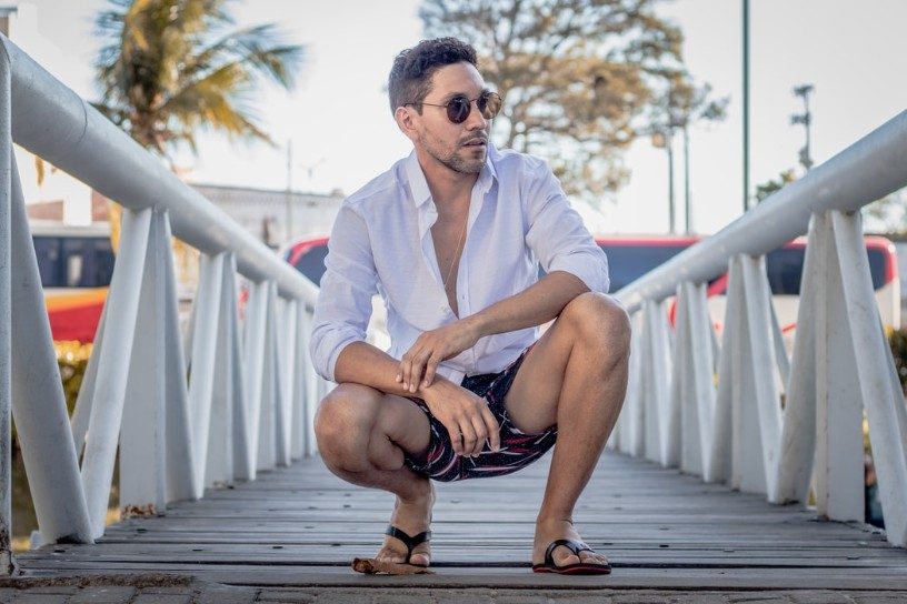 crouching man on a bridge in shirt and sunglasses