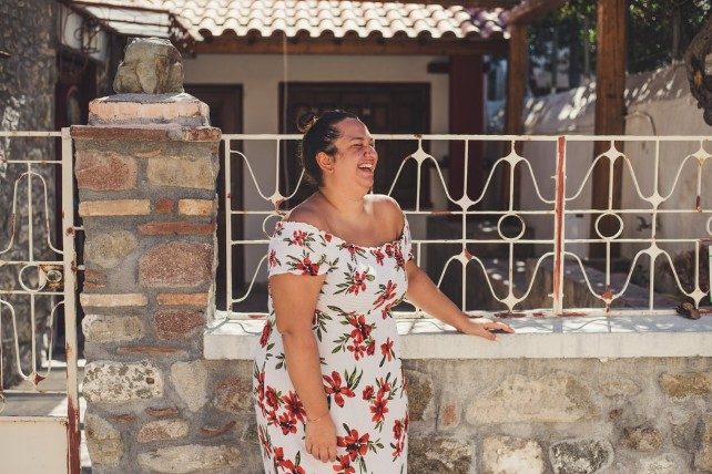 woman laughing with her hand on a wall outside a house