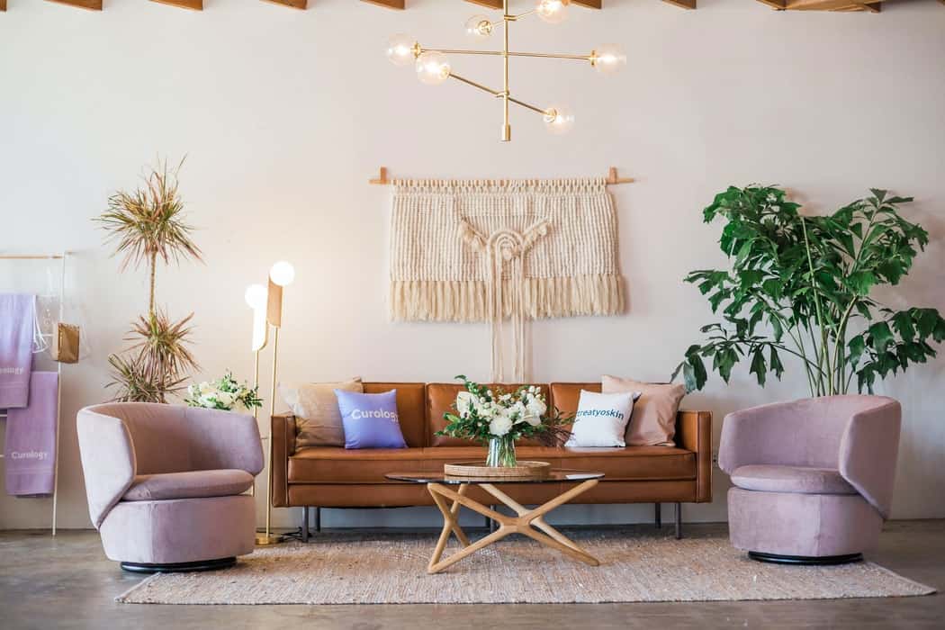 sofa in the middle of two purple round chairs with a coffee table, plants and lights