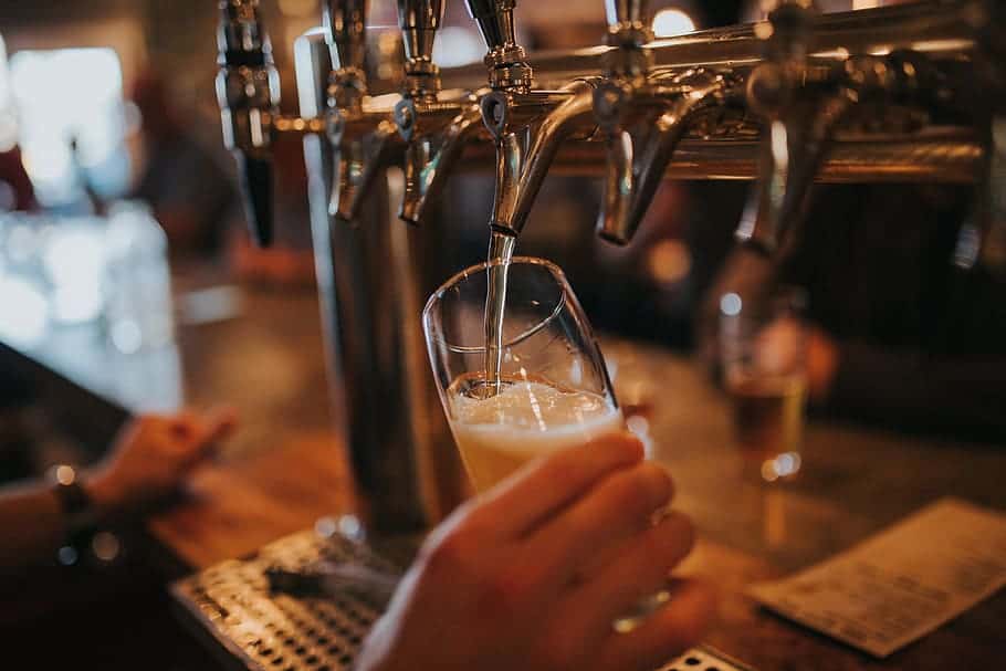 A person filling a beer on glass through beer tap