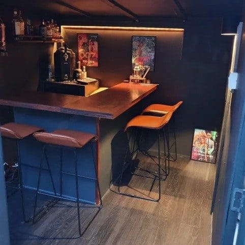 wooden summer house interior with a bar counter, stools and modern strip lighting