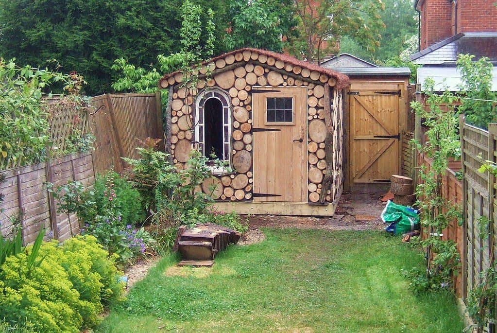 Mini wooden shed positioned at the corner of a small backyard