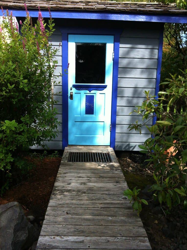 Mini blue garden shed with wooden pathway