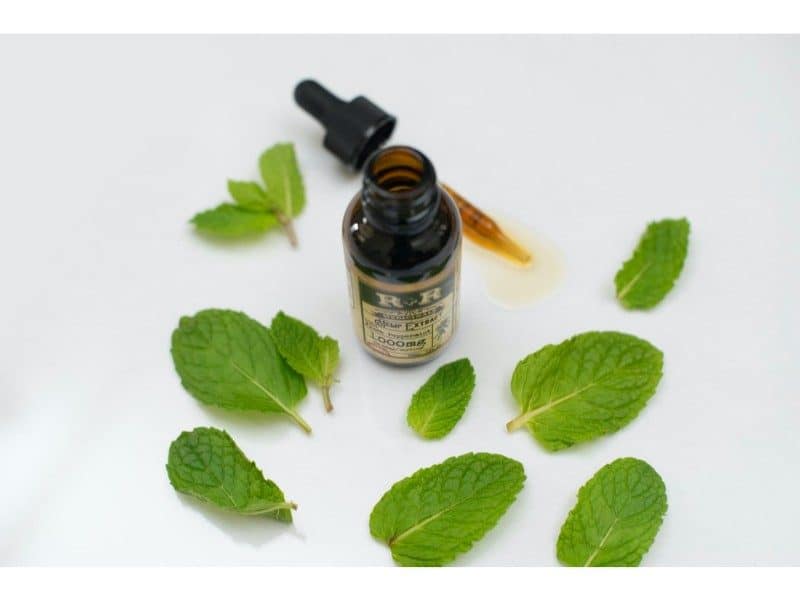 natural oil with leaves around a glass bottle with pipette