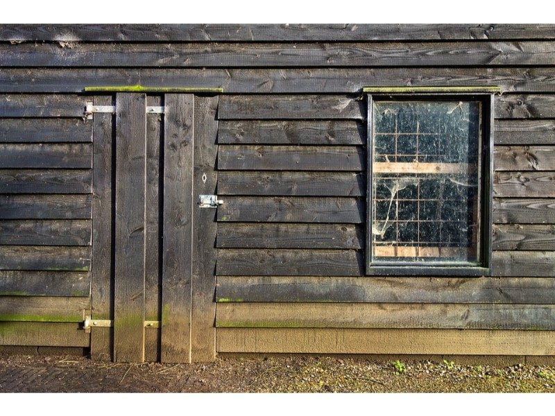 wooden shed with boarded up doors and grated window