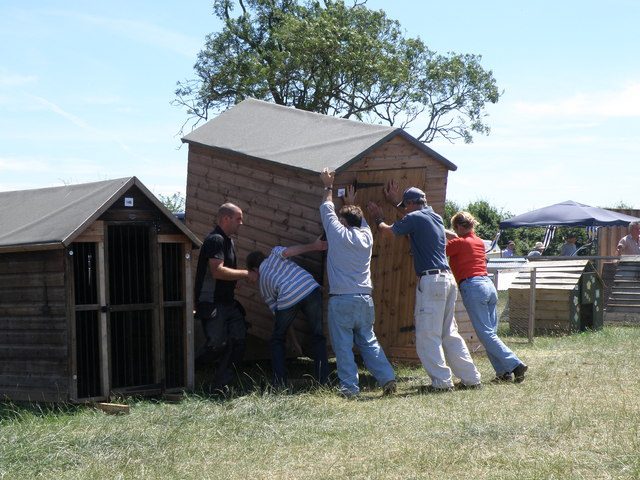 A group of people lifting a small shed
