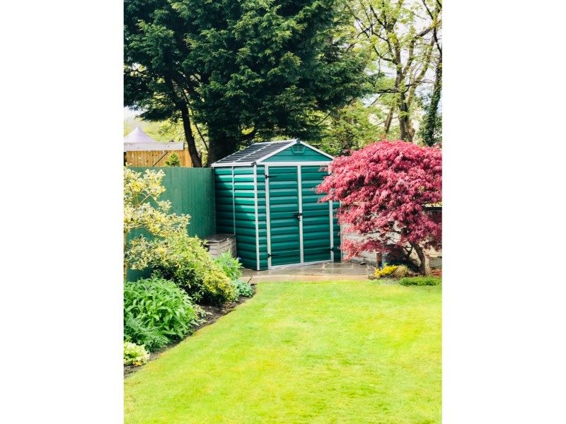 green shed at the bottom of a garden in the corner