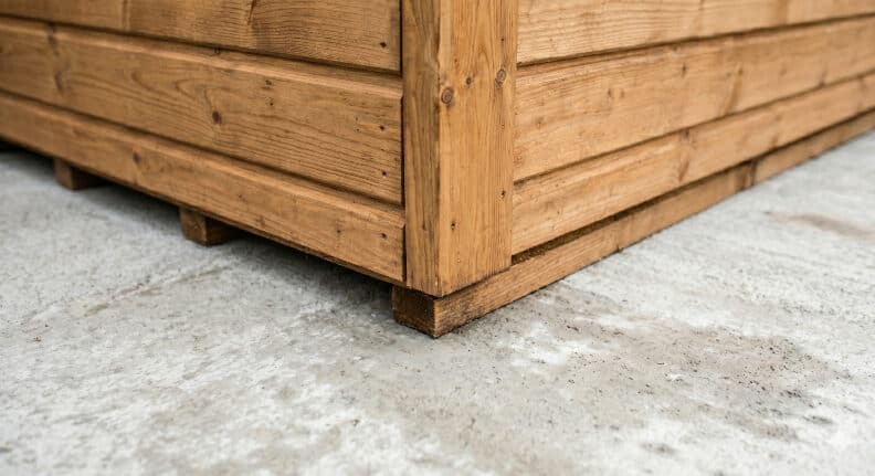 Close-up of a wooden shed corner sitting on a level concrete base