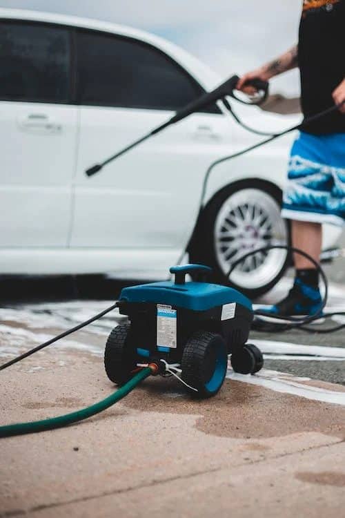 A man washing his car with a pressure washer