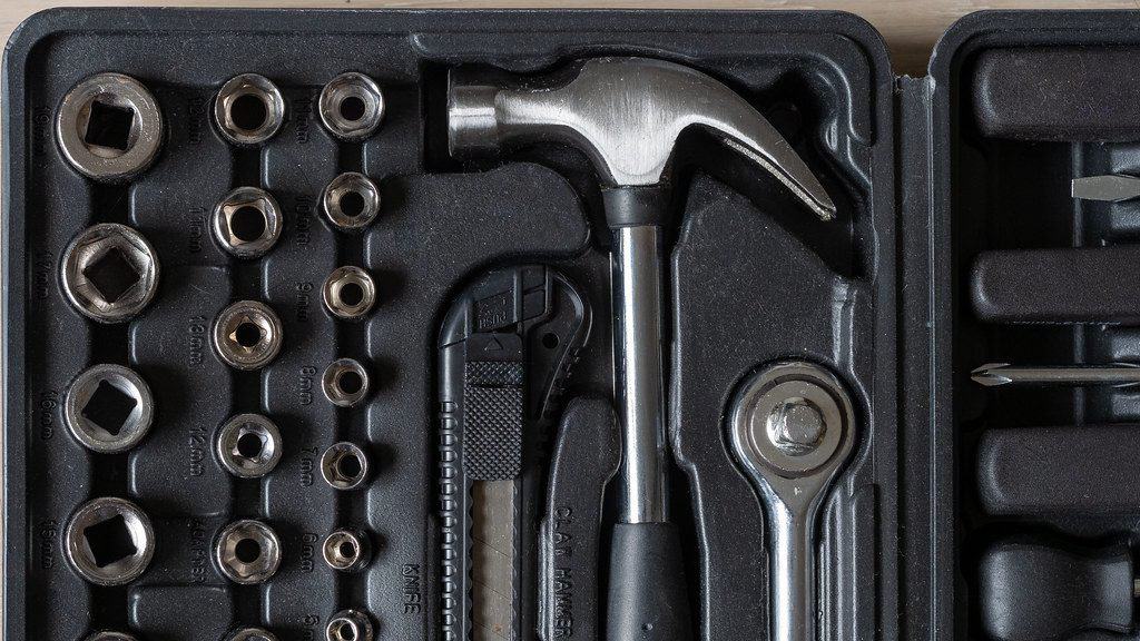 A toolbox with hammer and a variety of bolts and nuts