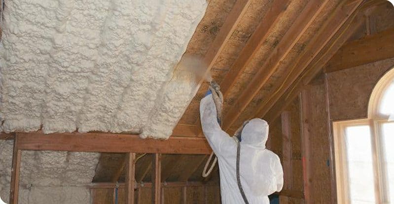A professional applying spray foam insulation in a shed