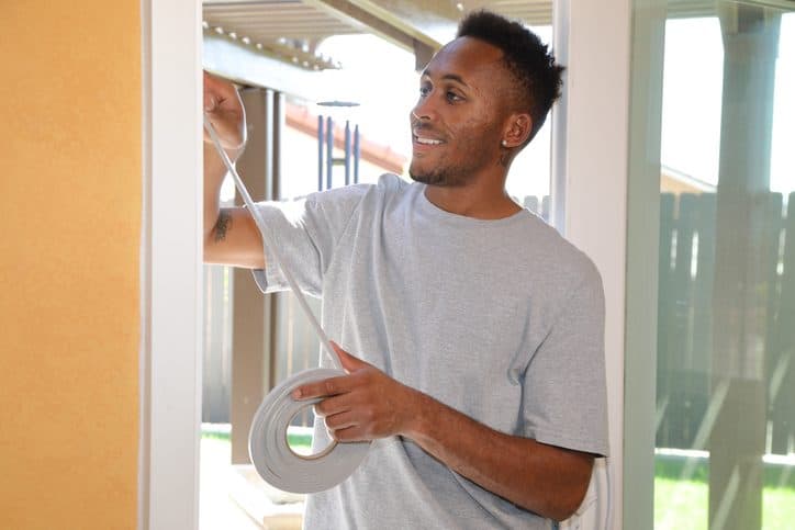 A man installing rubber strips on the side of a glass door