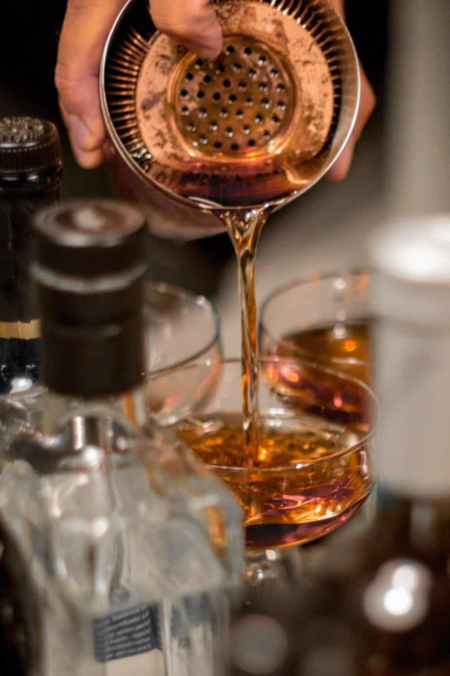 A person pouring a cocktail in a wine glass