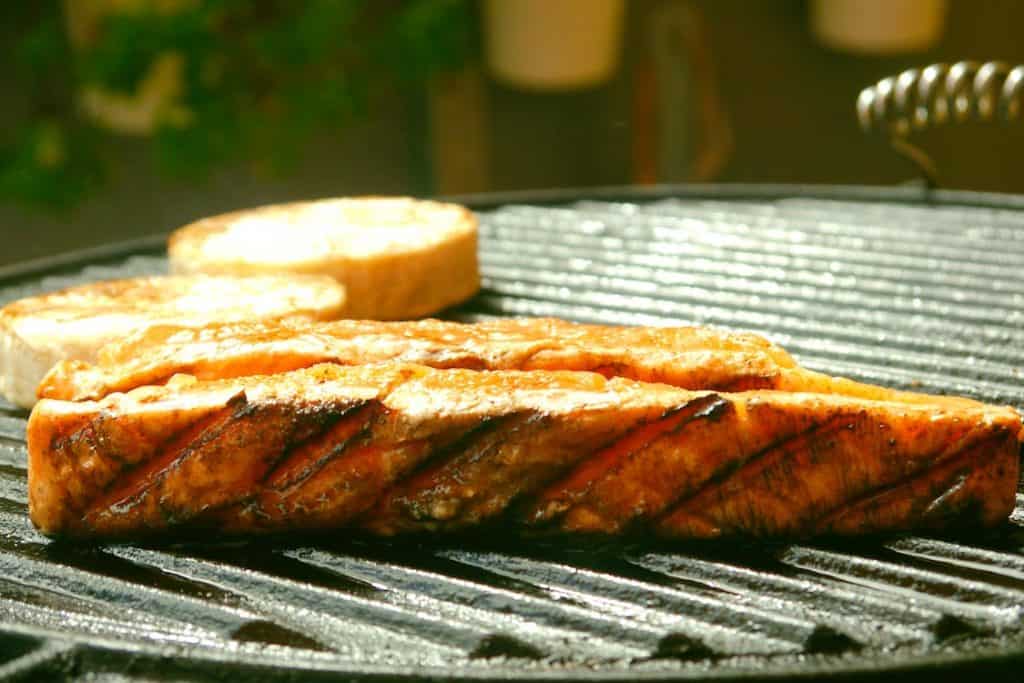 Salmon being grilled on a charcoal grill