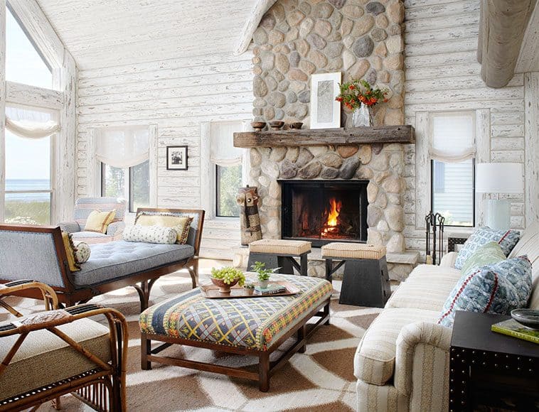 Shabby Chic Log Cabin Interior with cream coloured sofas an ottoman in front of a brick chimney fire
