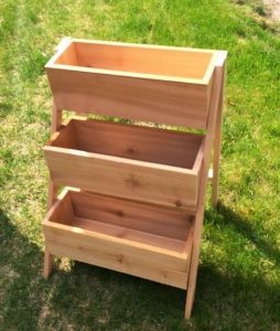 three wooden bin-like troughs stacked on top of one another in a sunny garden