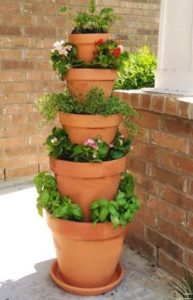 different sized plant pots stacked from the biggest on the ground to the smallest at the top, full with plants