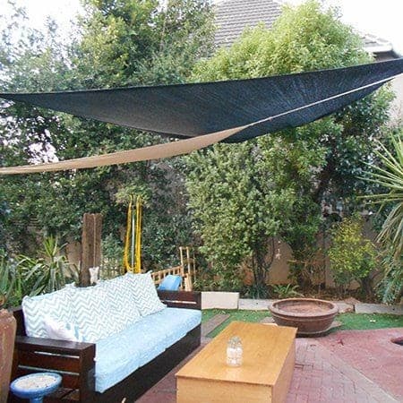 a large black tarpaulin sail covering a whole garden including a dark brown sofa, a light brown table and lots of plants in the background