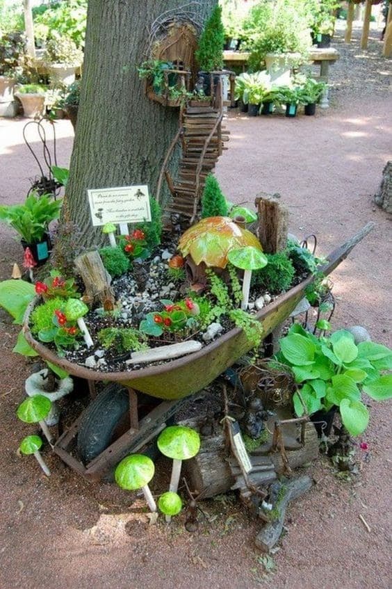 fairy garden with a wheelbarrow and stairs leading into a tree