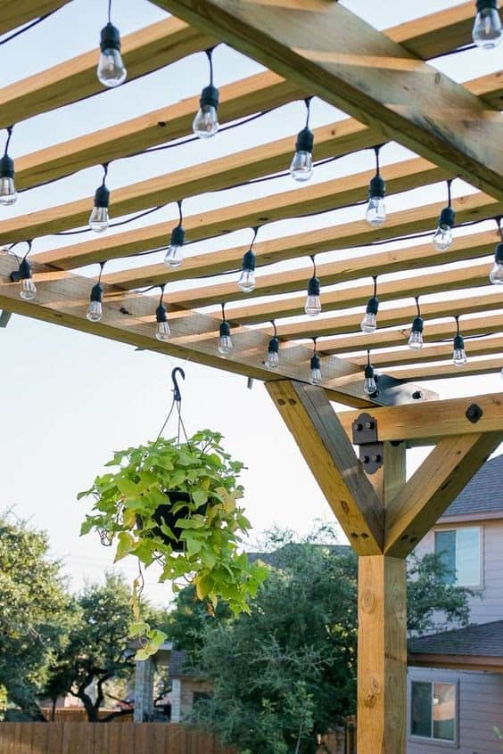 lightbulbs hanging down from a wooden pergola with slats spanning the width of the roof 