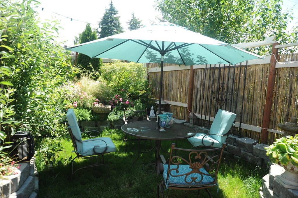 Small patio seating area with parasol and fencing for shade and privacy