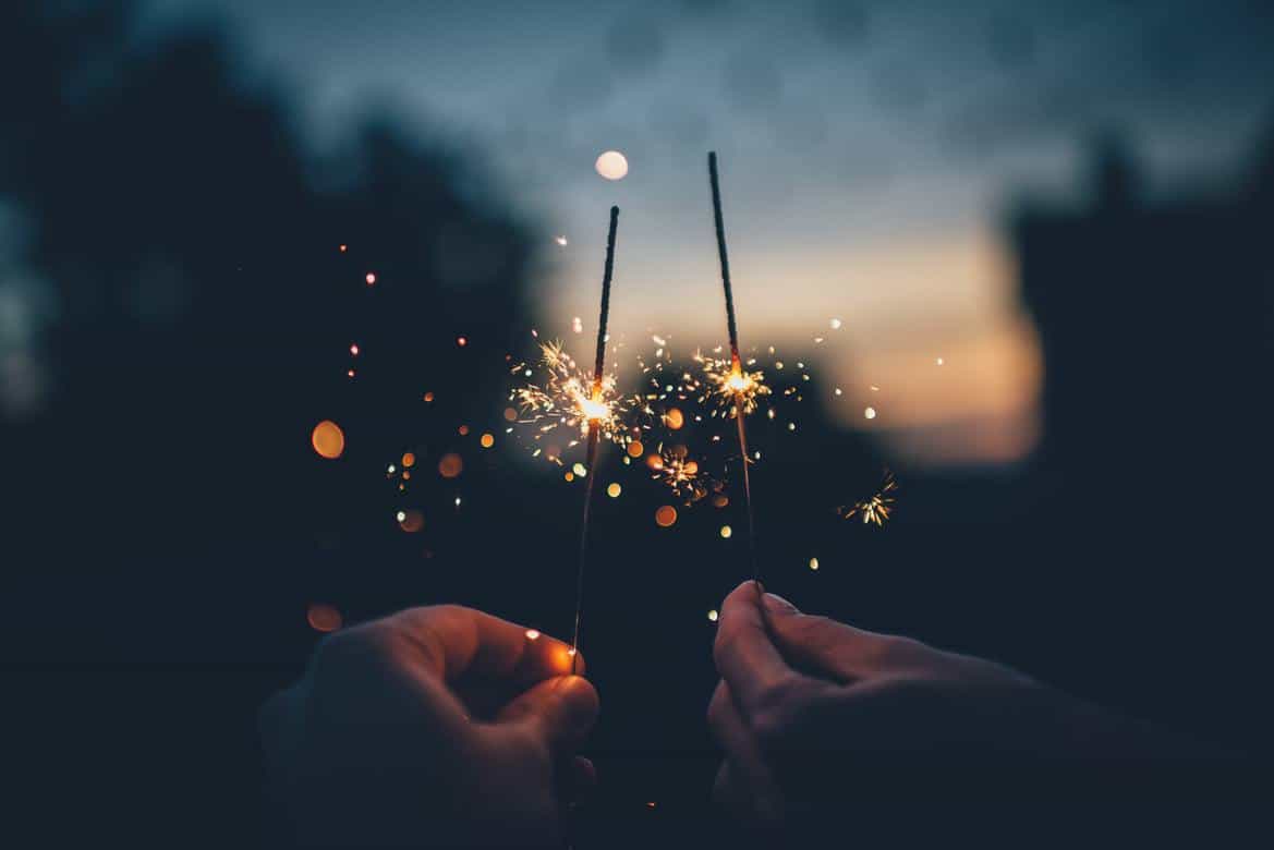 hands holding sparklers at night
