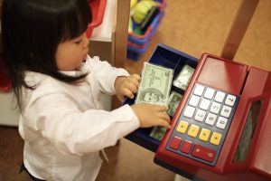 A child taking money from a toy cash register