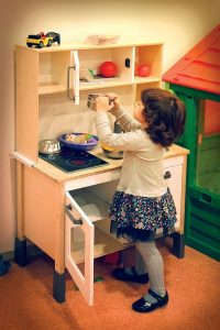 girl playing toy kitchen