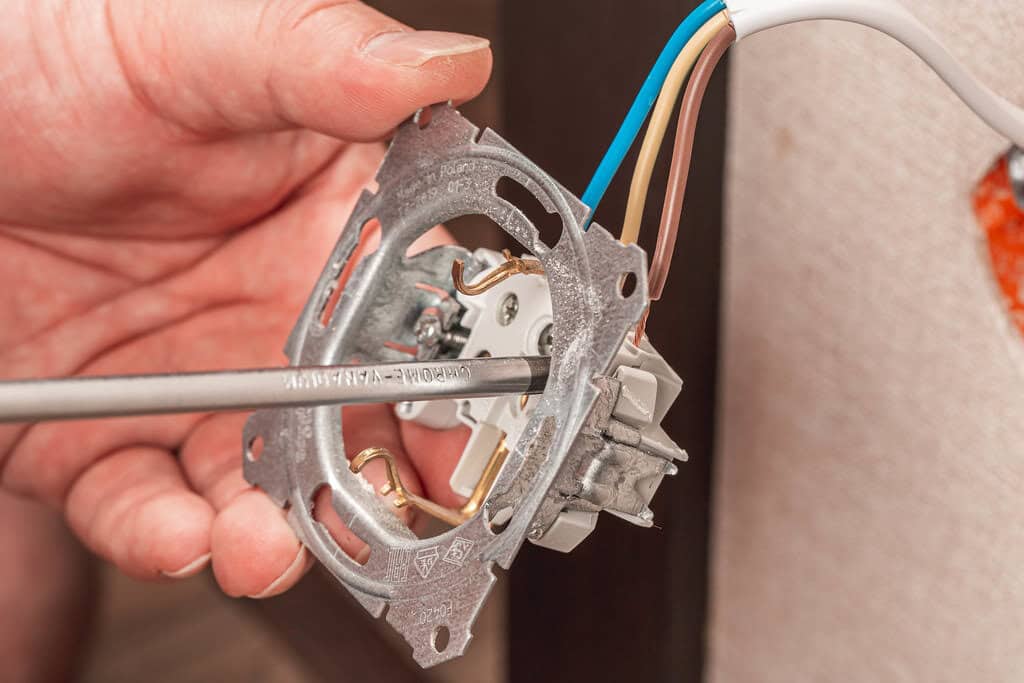Electrician installing wire into a plug and connecting the socket to the electrical wire.