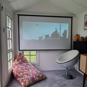 A movie projected onto a screen in a cosy summerhosue