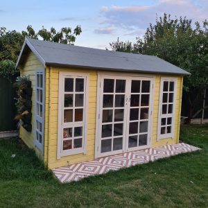 Yellow-painted summerhouse in grassy garden