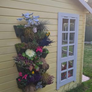 Flower planters hung on the side of a yellow summerhouse