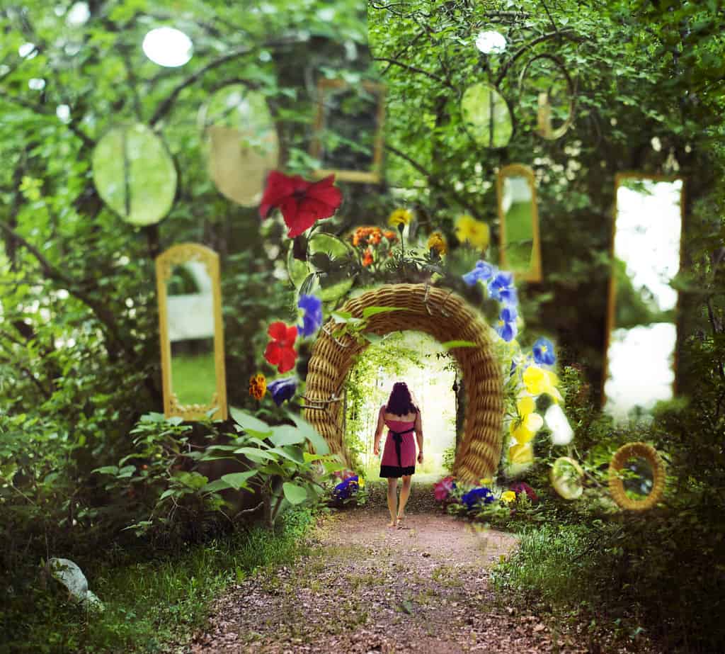 Woman in a pink dress strolling through a mirror garden.