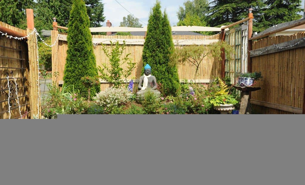 Mini garden with a Buddha statue protected by a bamboo retaining wall 