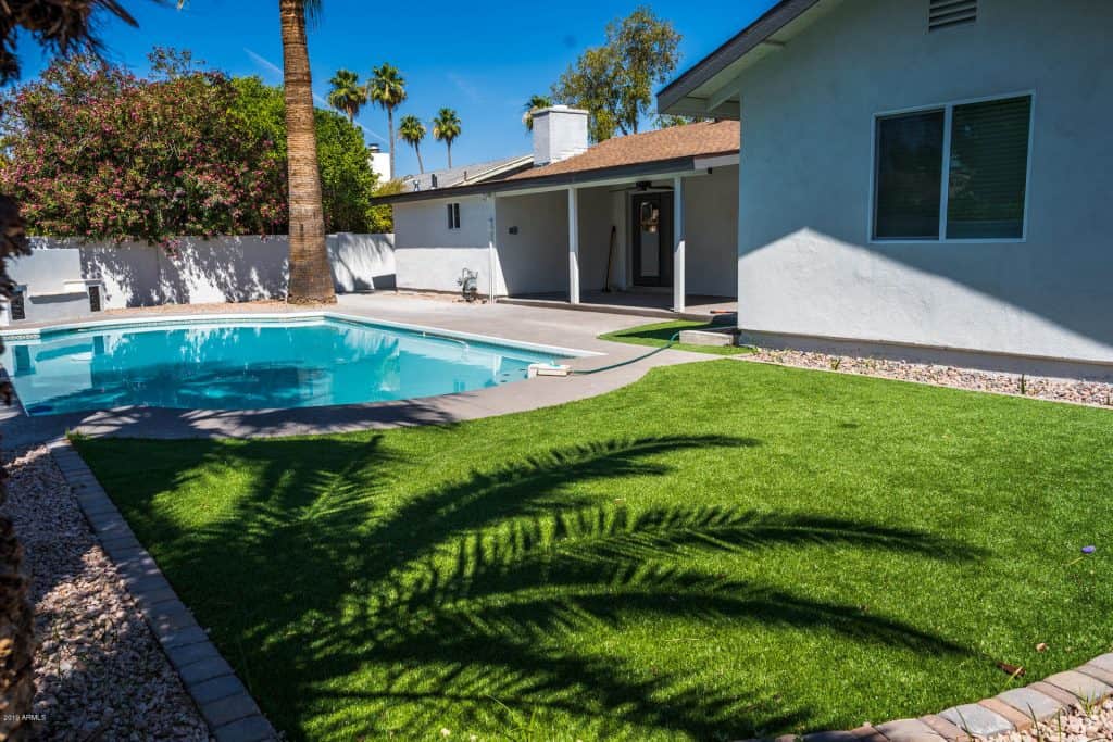 Artificial lawn landscaping near a backyard pool