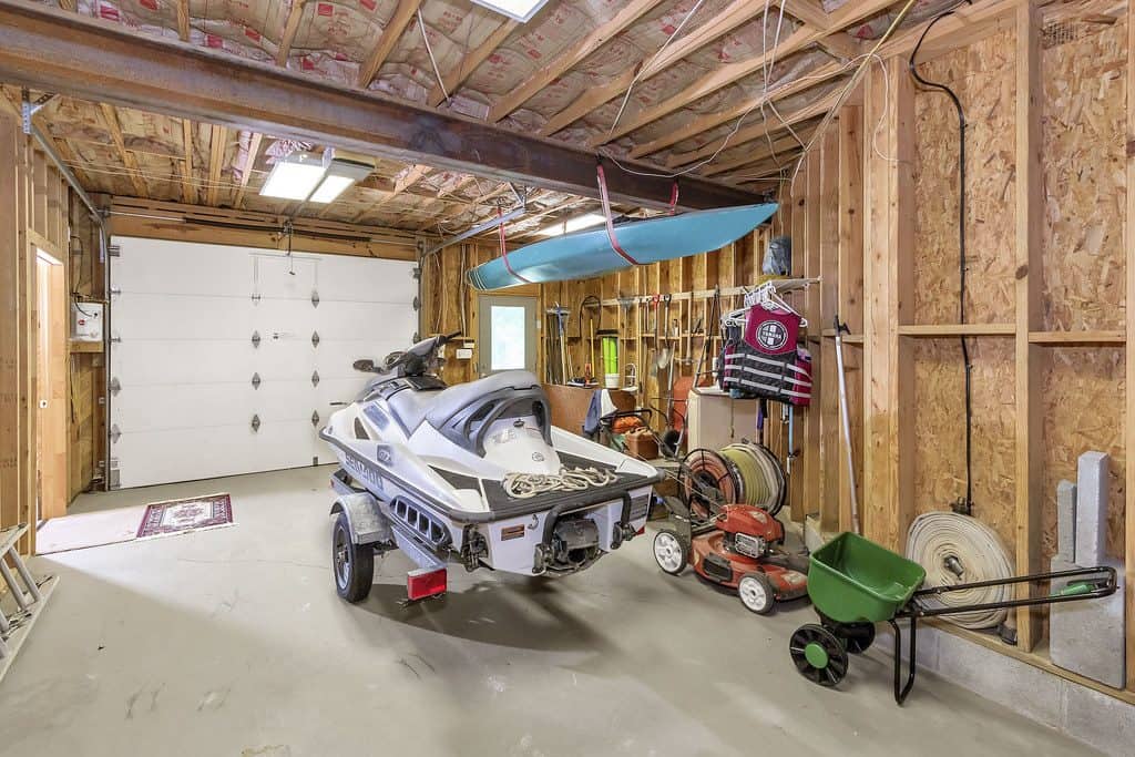 A boat hung on the ceiling bean of a garage