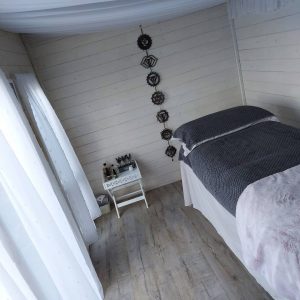 Log cabin therapy studio interior with bed decorated in grey and white