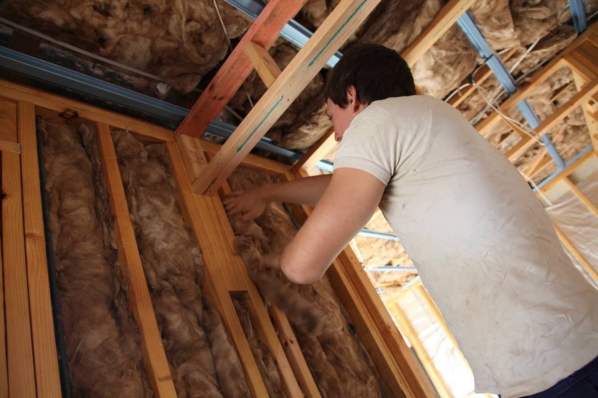 installing wool insulation up a ladder