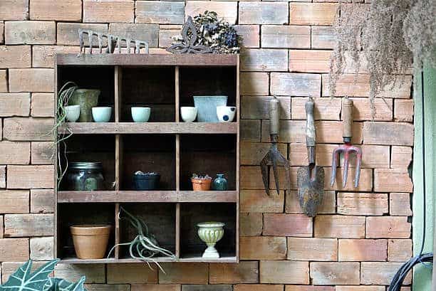 Gardener tools timber shelving mount on the brick wall with hanging garden tools.