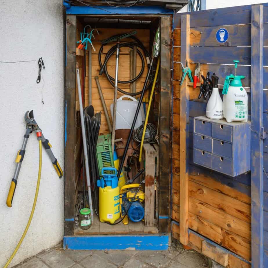 DIY corner shed filled with a variety of gardening equipment.