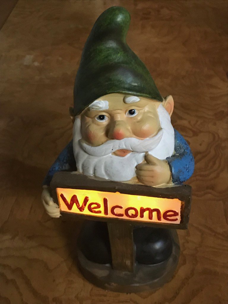 Solar-powered gnome holding a welcome sign