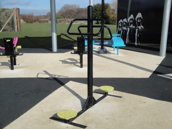 Outdoor gym equipment arranged in an open-air setting.