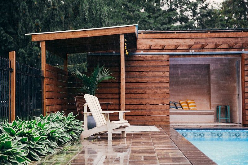 Half view of a backyard pool with wooden pool house
