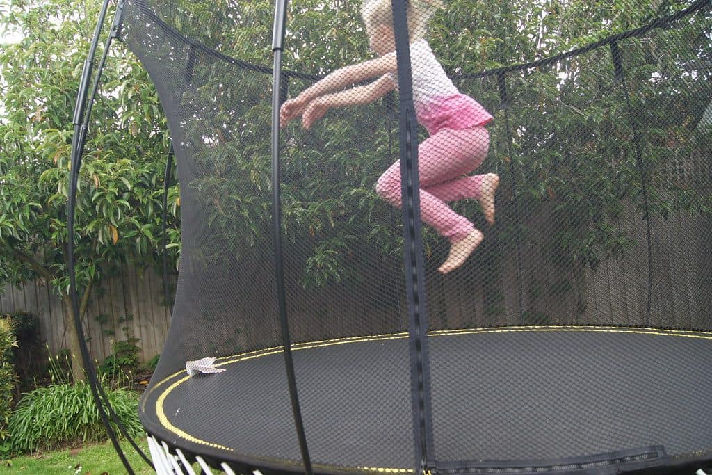 A kid jumping on an outdoor trampoline