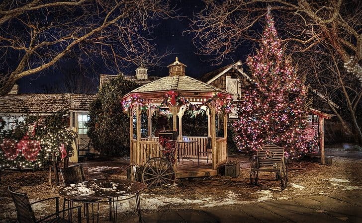 A garden with pergola and trees decorated for Christmas with lights