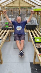 A gardener celebrating in their greenhouse