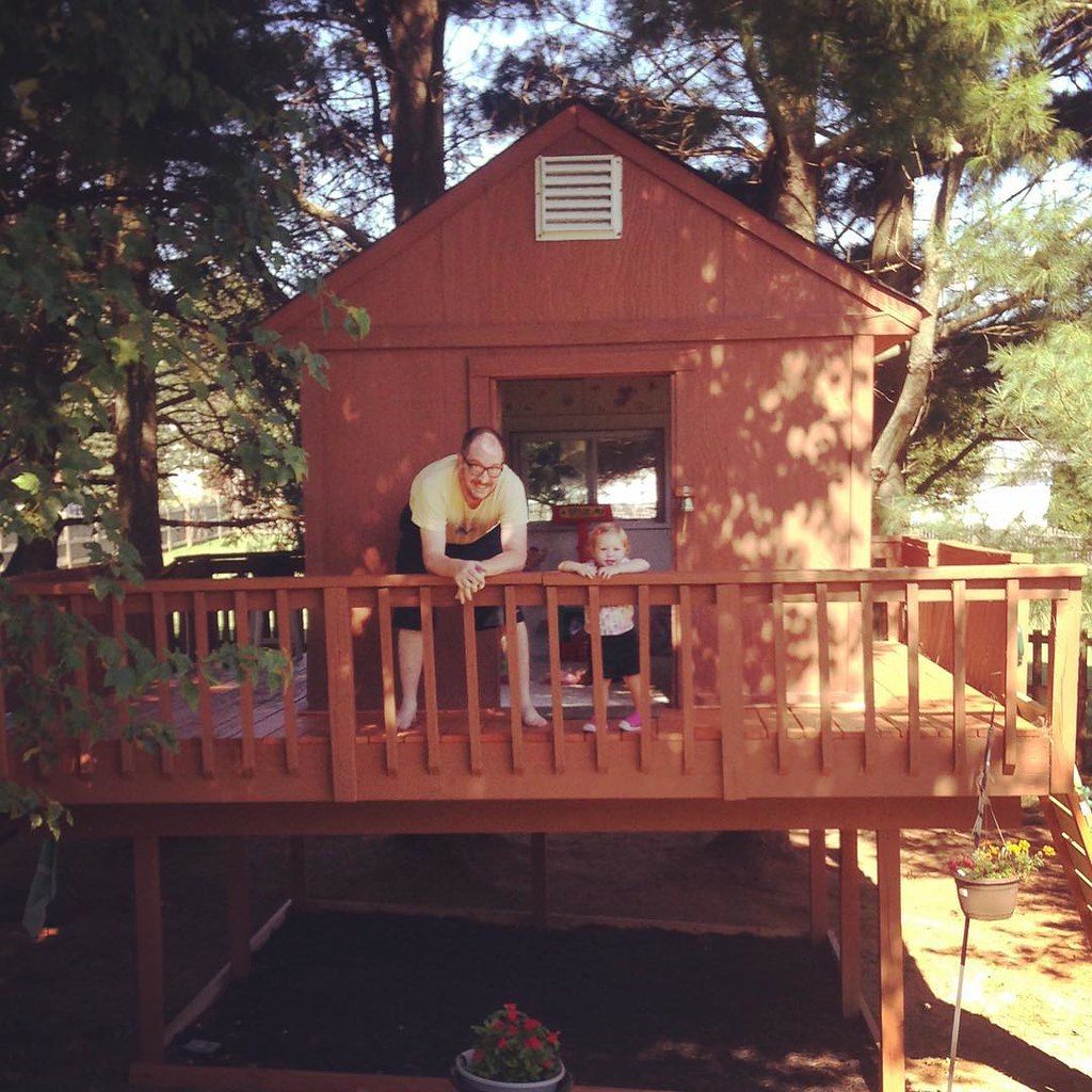 Father and daughter poses for a picture while on the tower Wendy house