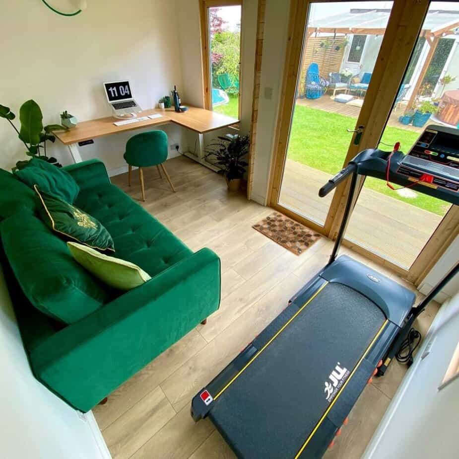 One of our customers shared their garden office setup, featuring an L-shaped desk in one corner, an inviting green sofa in the centre, and a treadmill in the other side.